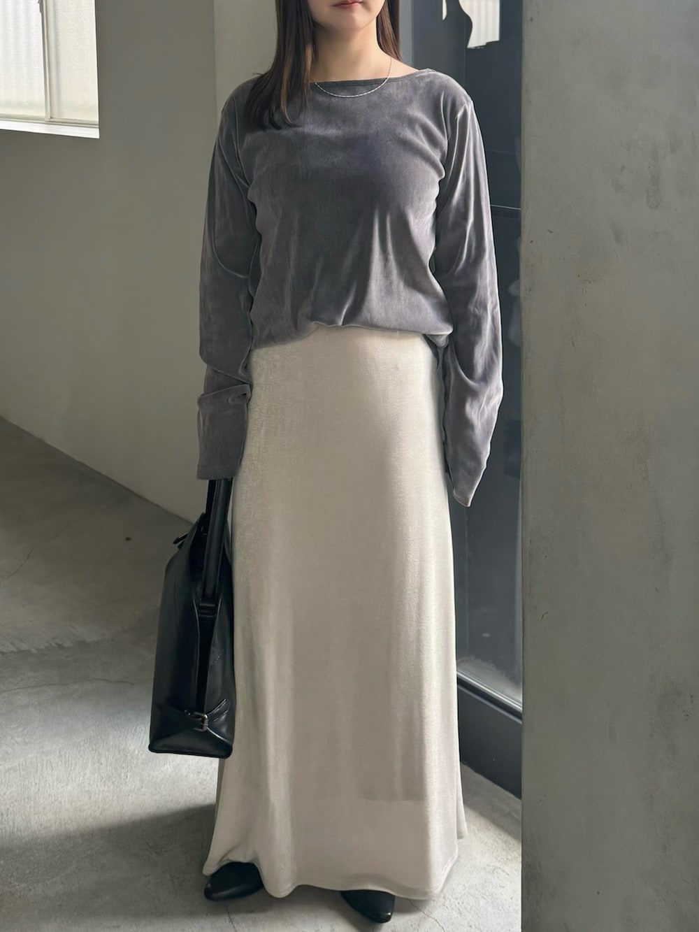 グレー系のTシャツ/カットソー、ホワイト系のスカート、ブラック系のハンドバッグを着用したレディースの冬コーディネートの2枚目の写真