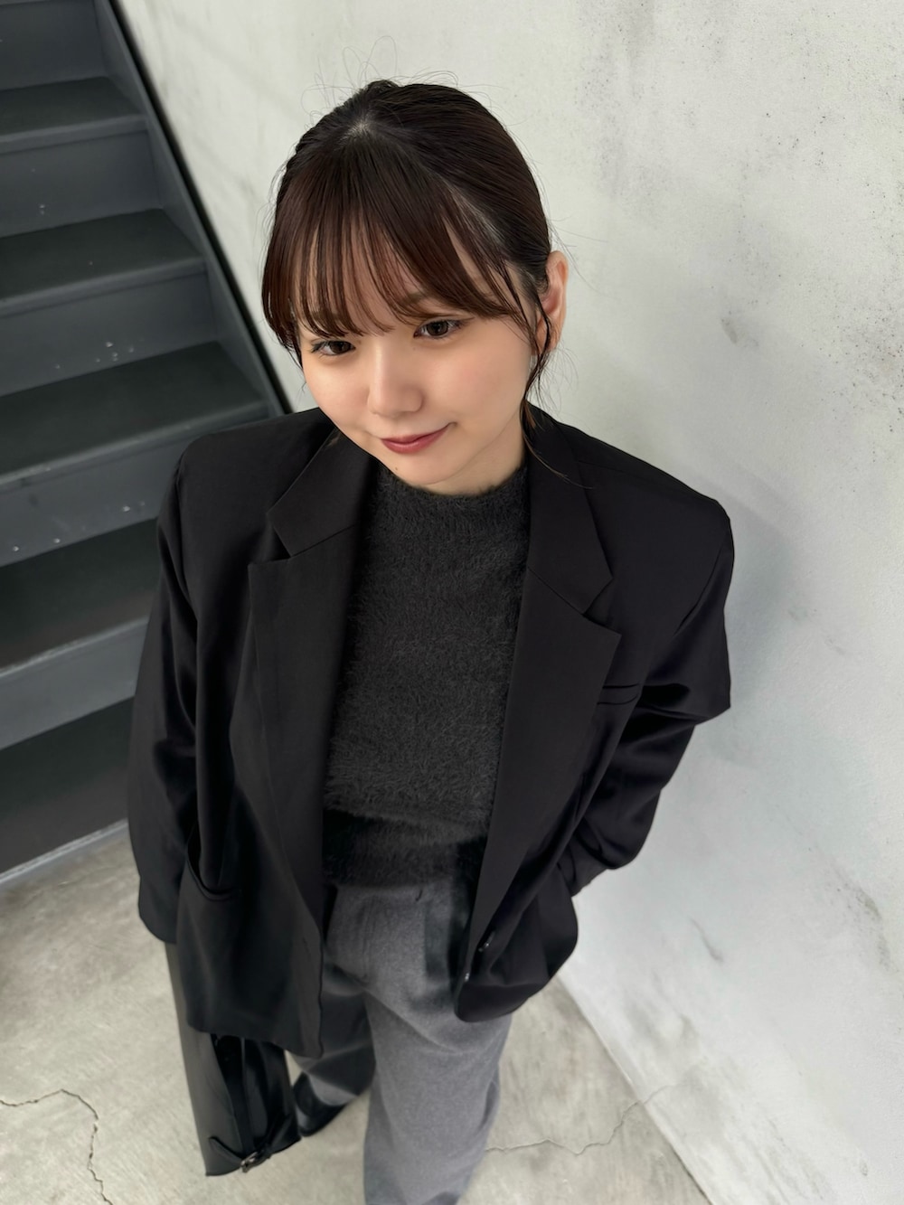 グレー系のニット/セーター、ブラック系のテーラードジャケット、グレー系のスラックスを着用したレディースの冬コーディネートの5枚目の写真