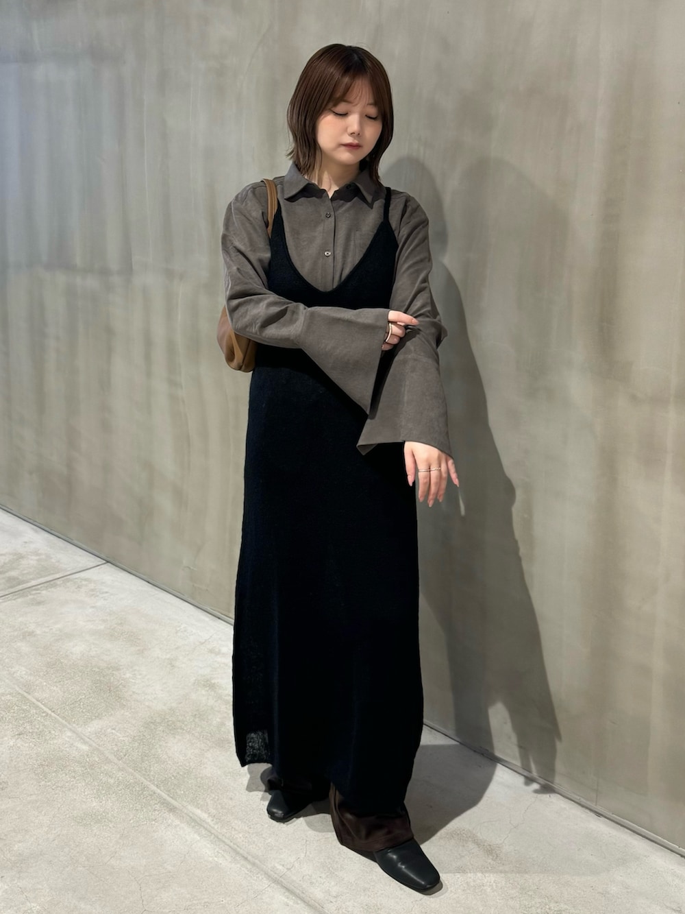 グレー系のシャツ/ブラウス、ブラック系のワンピース、ブラック系のスリッポンを着用したレディースの秋コーディネートの2枚目の写真