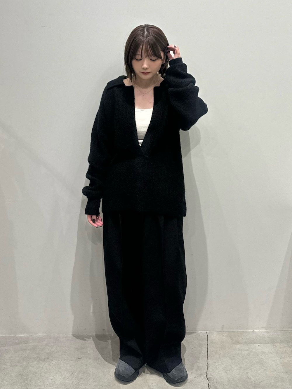 ブラック系のニット/セーター、ホワイト系のキャミソール、ブラック系のスラックスを着用したレディースの秋コーディネートの2枚目の写真