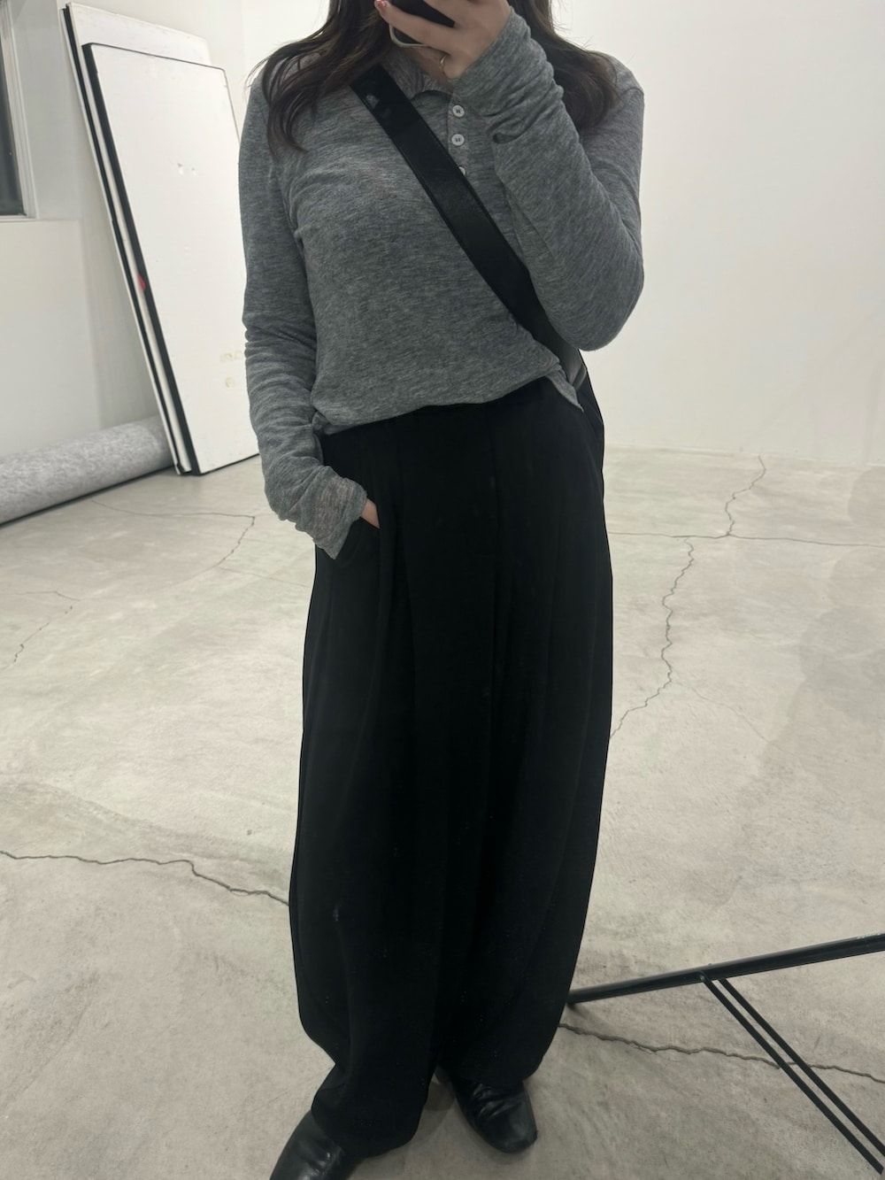 ブラック系のスラックス、グレー系のTシャツ/カットソー、ブラック系のショルダーバッグを着用したレディースの冬コーディネートの3枚目の写真