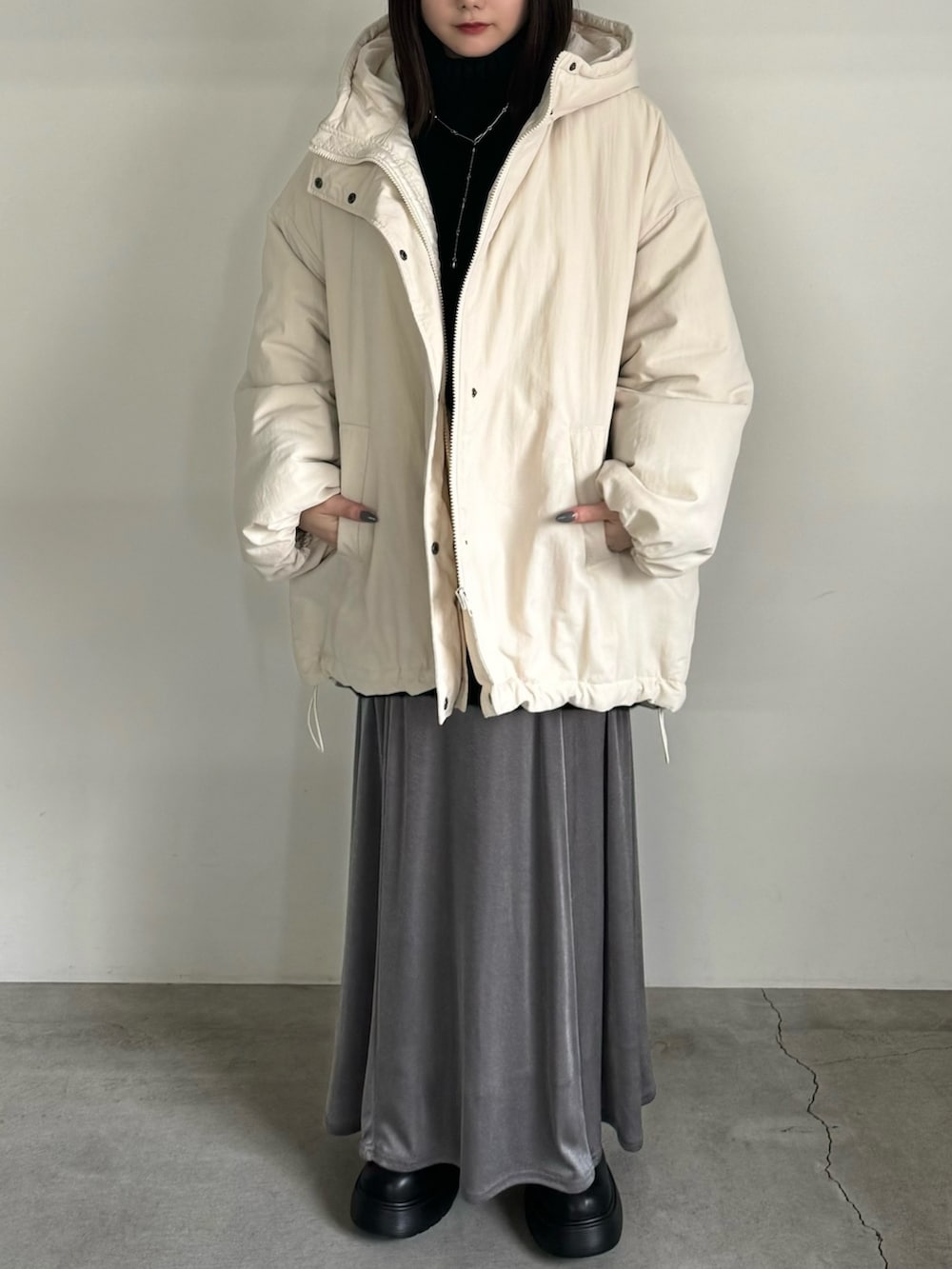 ホワイト系のダウンジャケット/コート、グレー系のスカート、ブラック系のブーツを着用したレディースの冬コーディネートの2枚目の写真