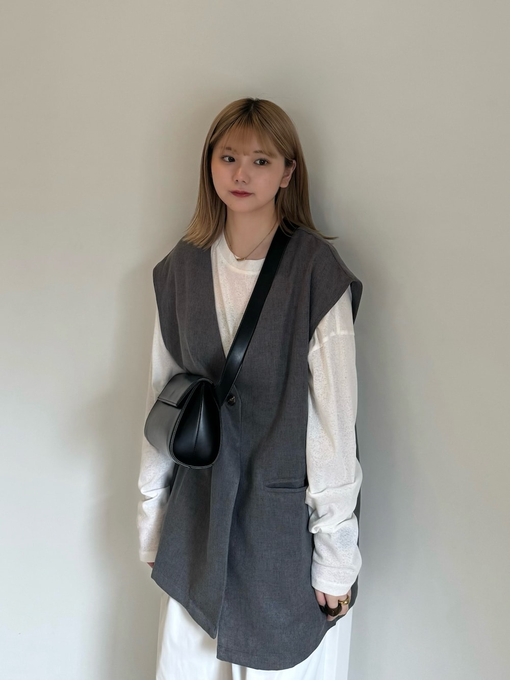 グレー系のベスト、ホワイト系のTシャツ/カットソー、ブラック系のキャミソールを着用したレディースの春コーディネートの5枚目の写真