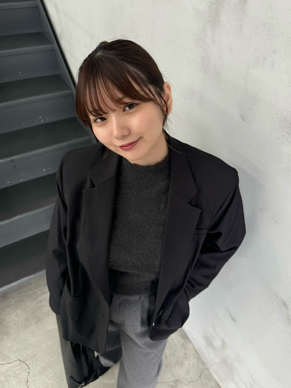 グレー系のニット/セーター、ブラック系のテーラードジャケット、グレー系のスラックスを着用したレディースの冬コーディネートの6枚目の写真