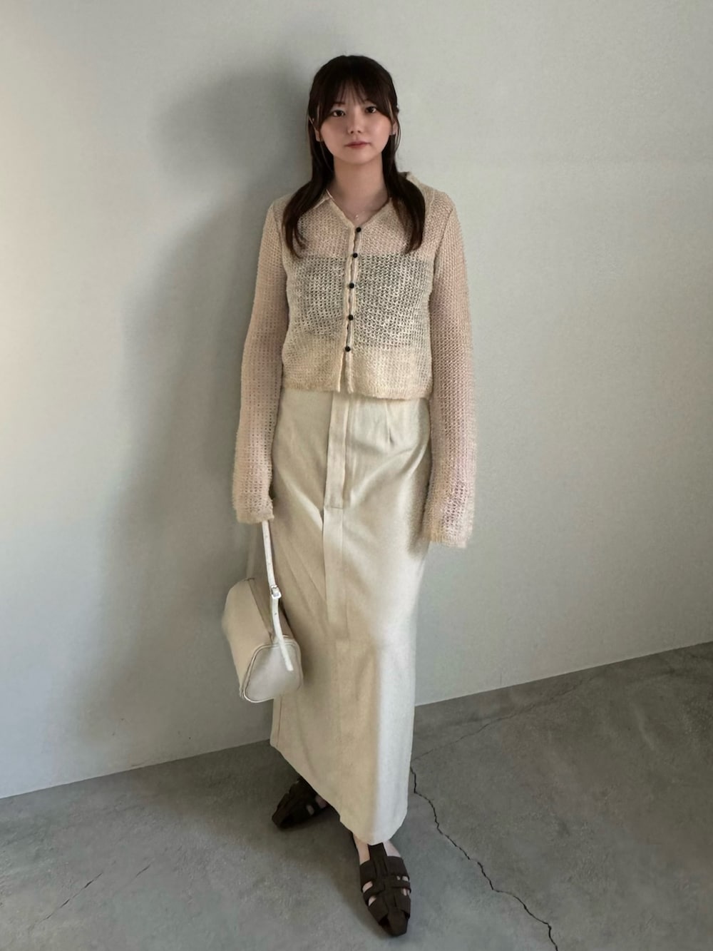 ベージュ系のカーディガン/ボレロ、ブラック系のキャミソール、ホワイト系のスカートを着用したレディースの春コーディネートの2枚目の写真