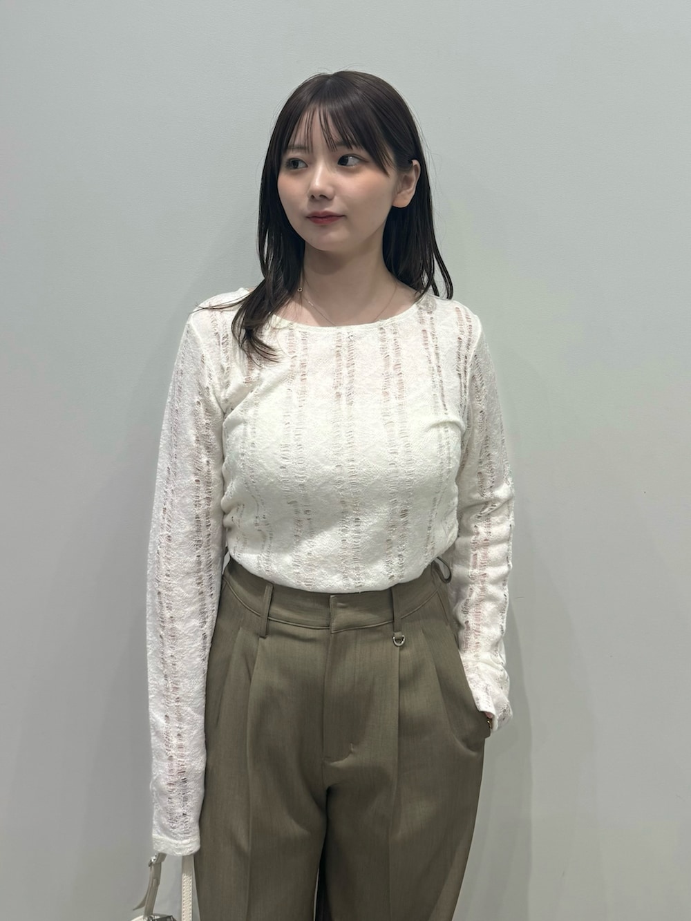 ブラウン系のスラックス、ホワイト系のハンドバッグ、ホワイト系のキャミソールを着用したレディースの春コーディネートの3枚目の写真