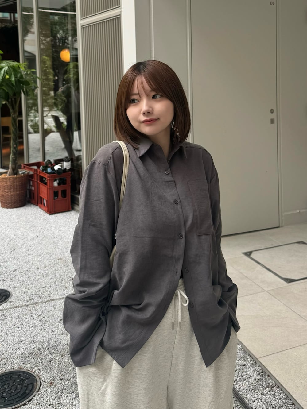 グレー系のシャツ/ブラウス、ベージュ系のスウェットパンツ、ホワイト系のハンドバッグを着用したレディースの秋コーディネートの4枚目の写真