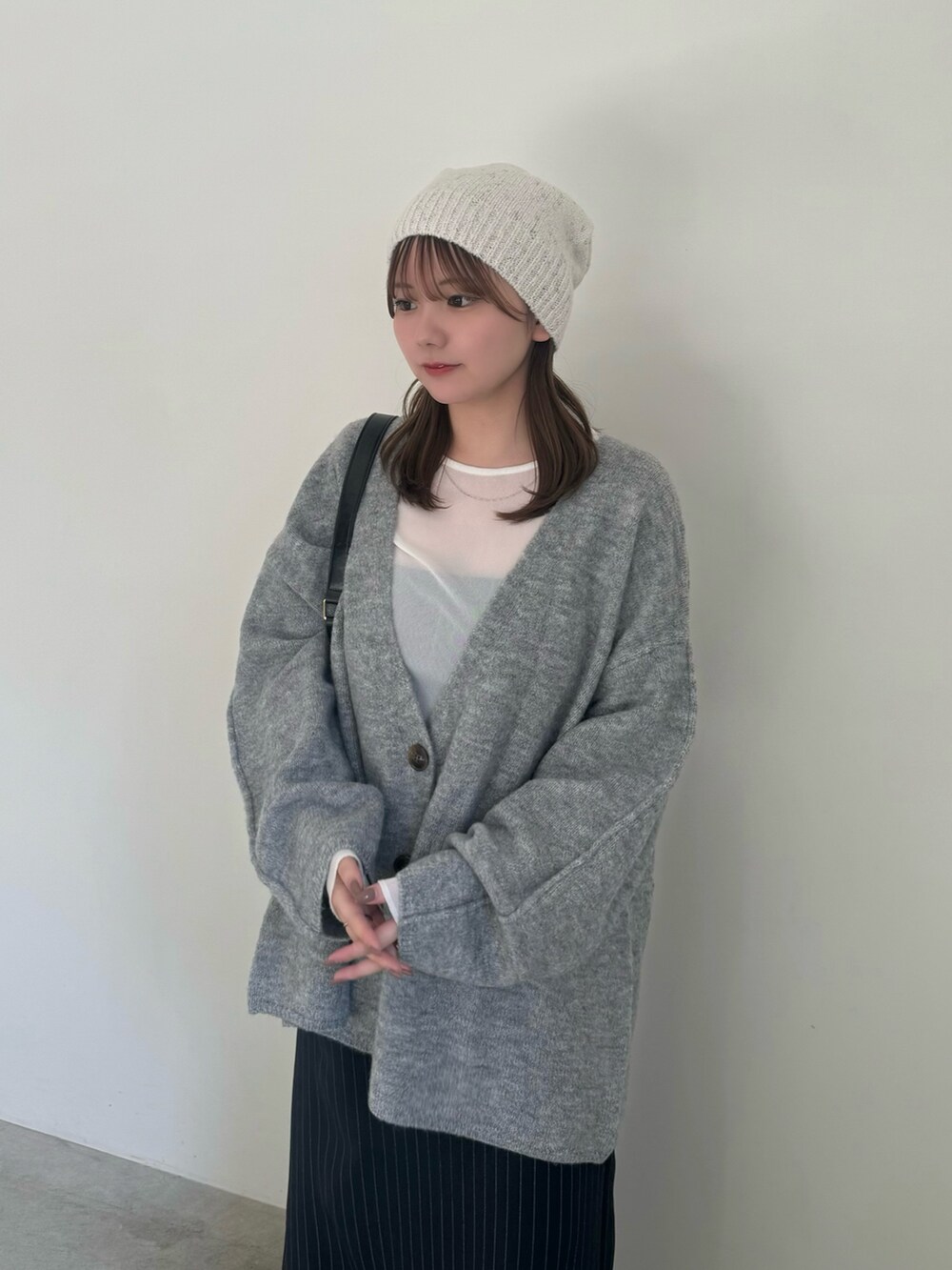 ベージュ系のカーディガン/ボレロ、ホワイト系のTシャツ/カットソー、ブルー系のスカートを着用したレディースの秋コーディネートの4枚目の写真