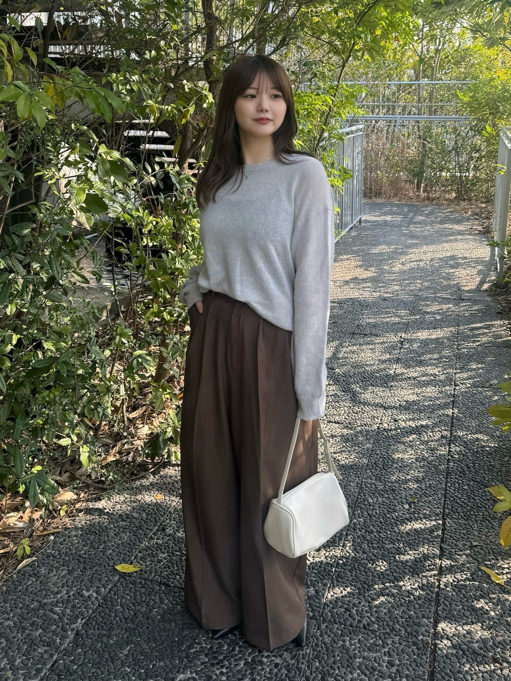 ブラック系のキャミソール、グレー系のニット/セーター、ブラウン系のスラックスを着用したレディースの春コーディネートの4枚目の写真