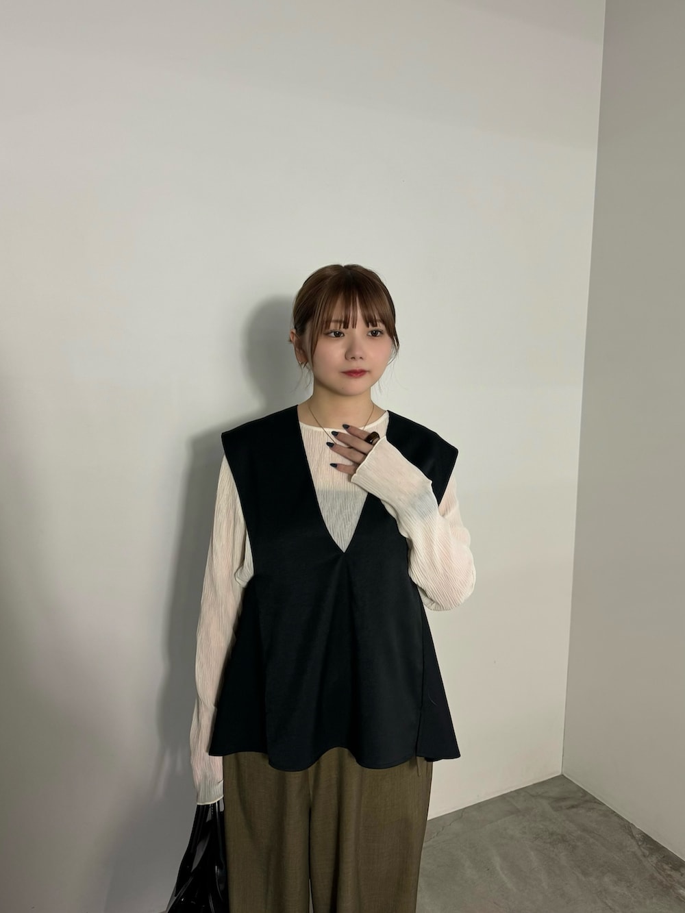 ブラック系のベスト、ブラウン系のスラックス、ホワイト系のTシャツ/カットソーを着用したレディースの冬コーディネートの3枚目の写真