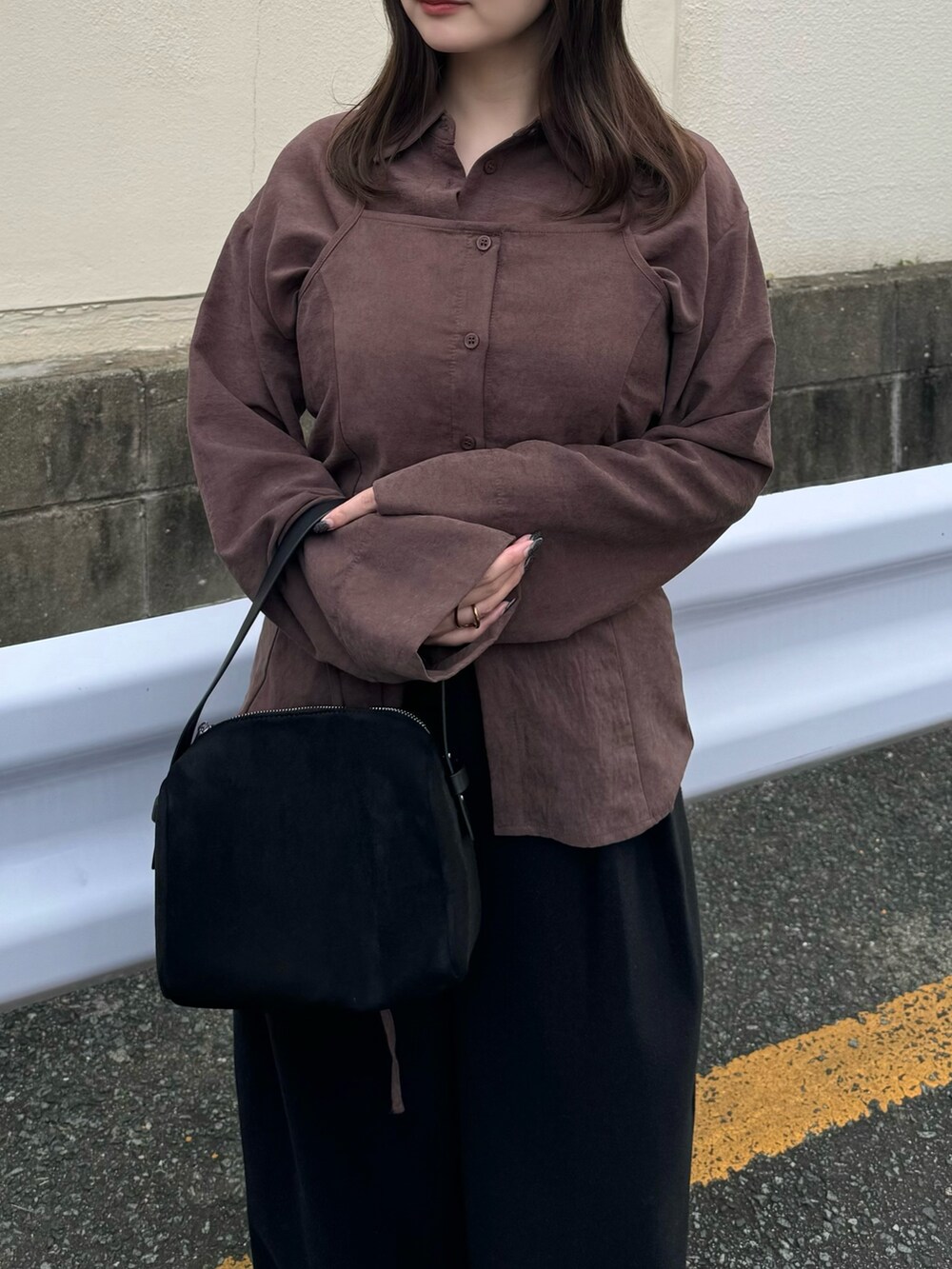 ブラック系のスラックス、ブラック系のハンドバッグ、ブラック系のブーツを着用したレディースの秋コーディネートの3枚目の写真