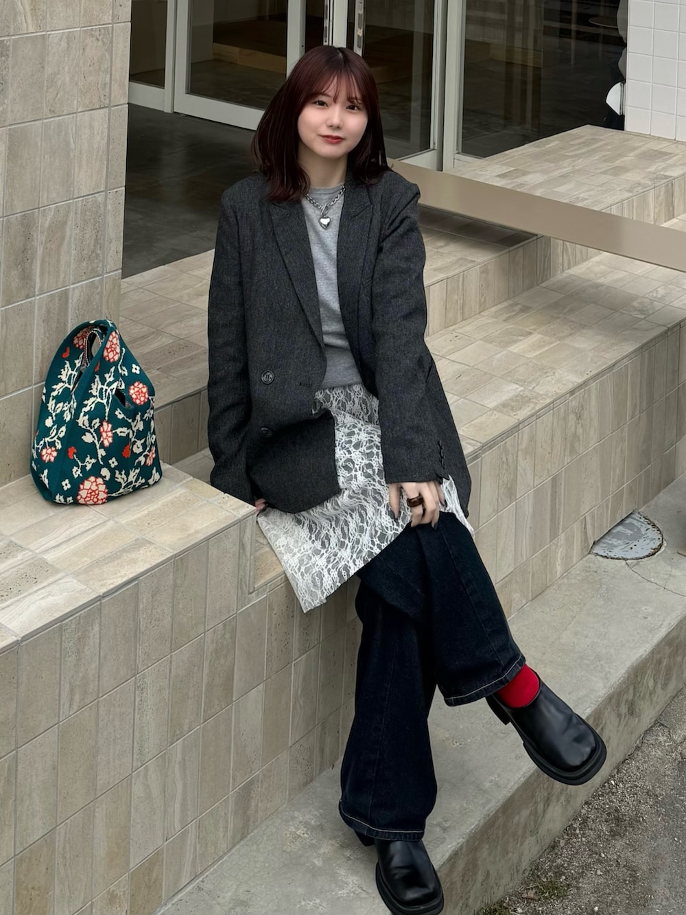 グレー系のテーラードジャケット、ホワイト系のスカート、ブルー系のデニムパンツを着用したレディースの冬コーディネートの2枚目の写真