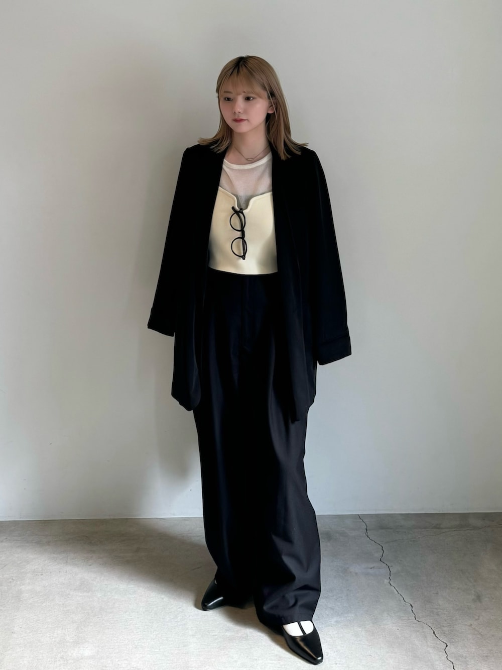 ブラック系のテーラードジャケット、ホワイト系のニット/セーター、ホワイト系のベストを着用したレディースの春コーディネートの3枚目の写真