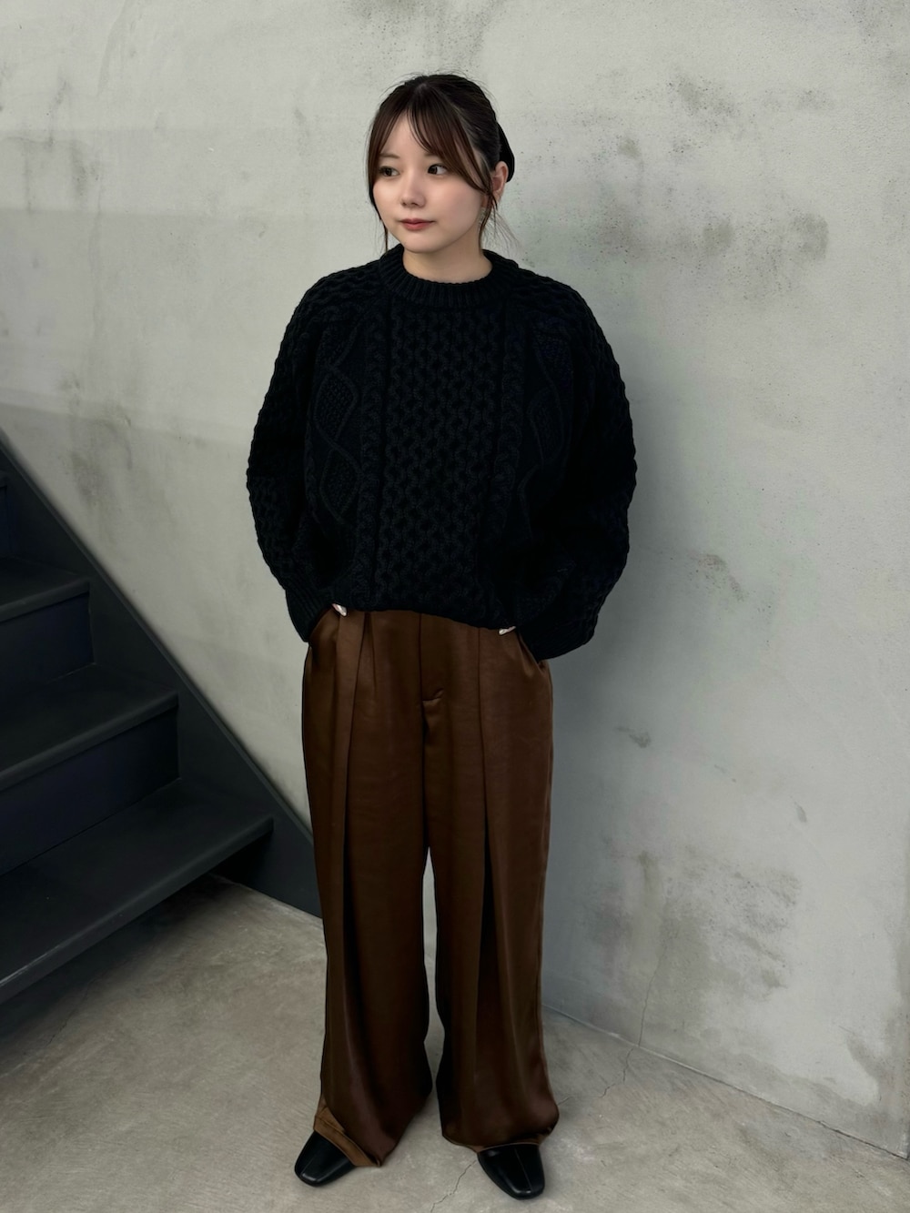 ブラック系のニット/セーター、ブラウン系のスラックス、ブラック系のブーツを着用したレディースの秋コーディネートの2枚目の写真