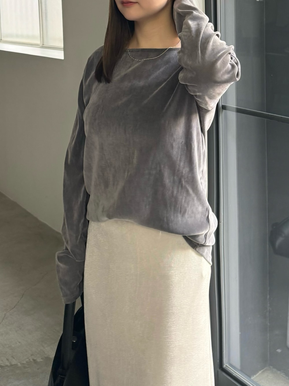 グレー系のTシャツ/カットソー、ホワイト系のスカート、ブラック系のハンドバッグを着用したレディースの冬コーディネートの3枚目の写真