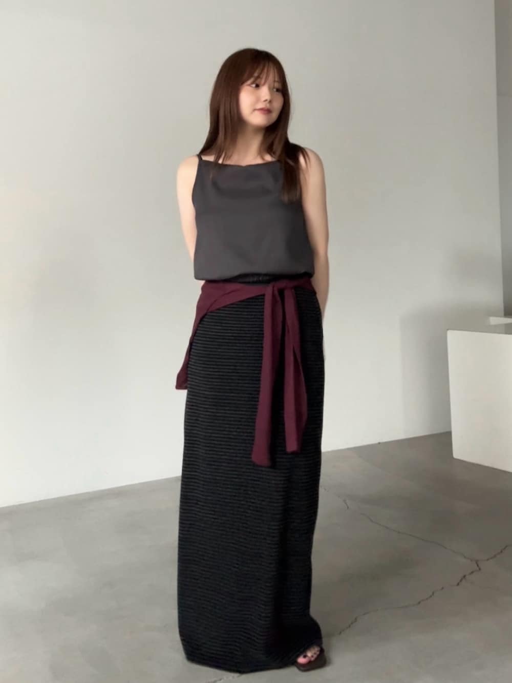 グレー系のキャミソール、レッド系のカーディガン/ボレロ、ブラック系のスカートを着用したレディースの夏コーディネートの2枚目の写真