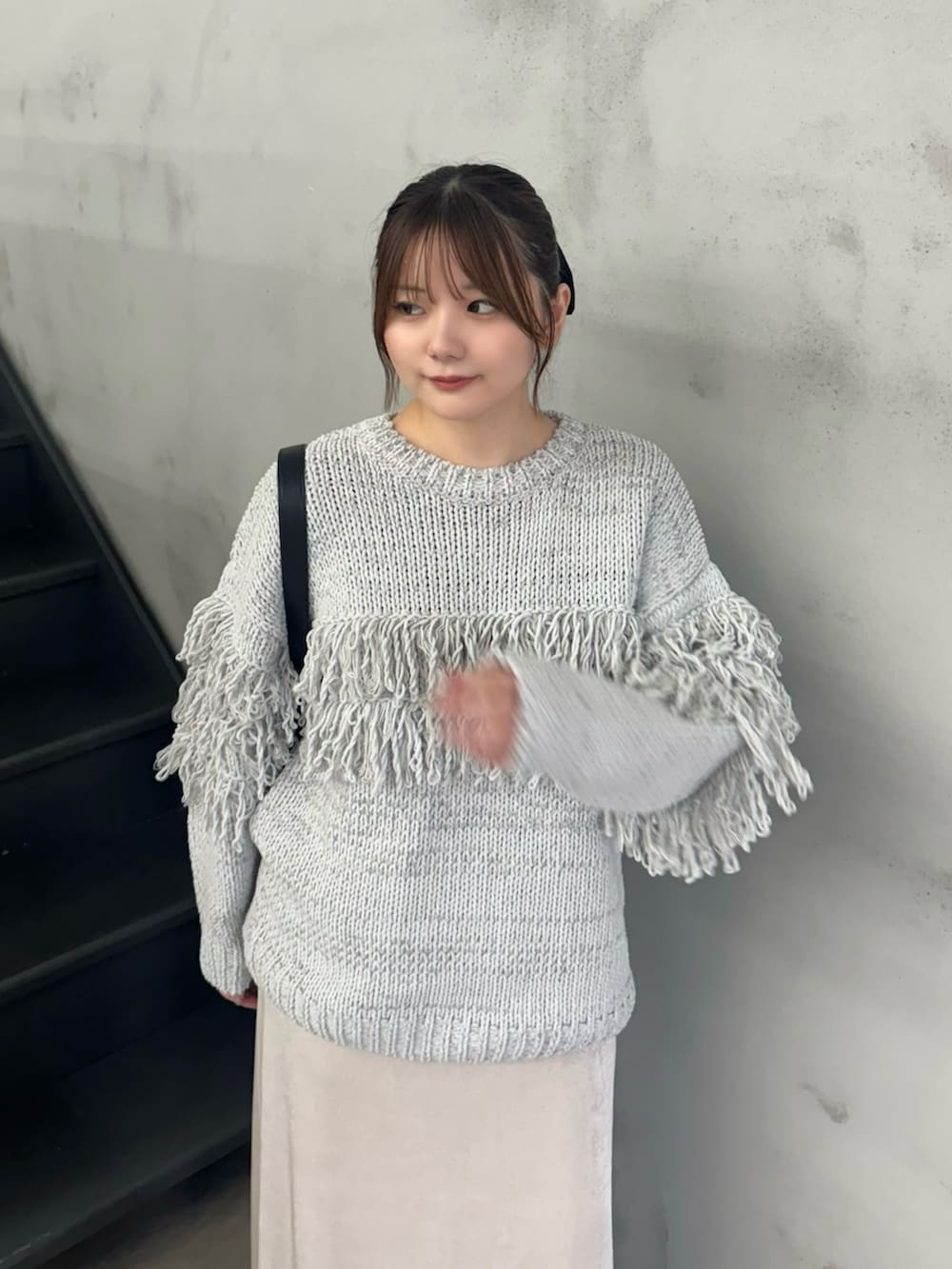 グレー系のニット/セーター、ホワイト系のスカート、ブラック系のショルダーバッグを着用したレディースの秋コーディネートの3枚目の写真