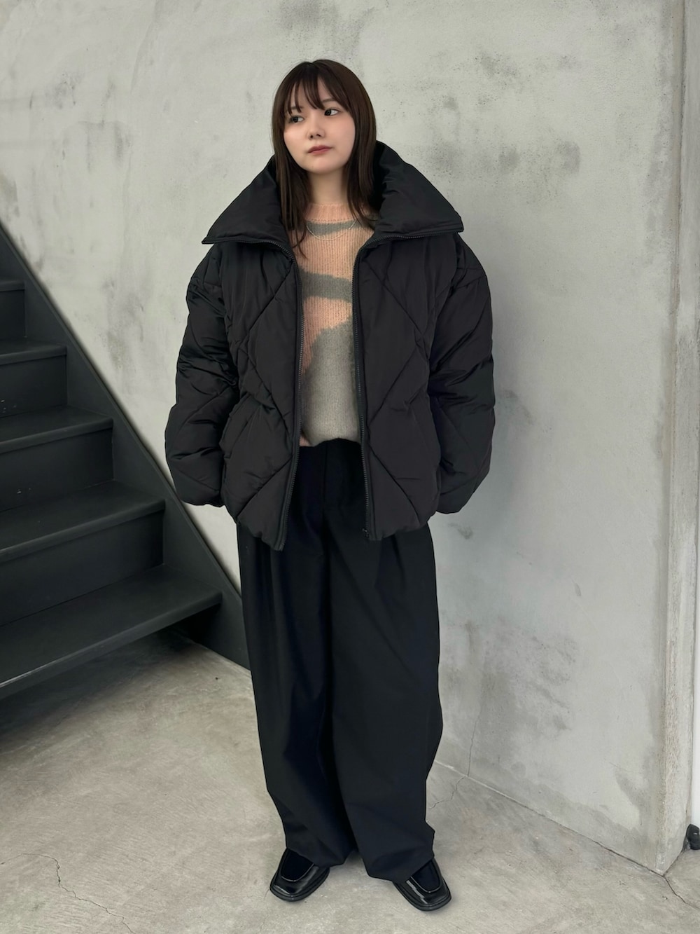 ピンク系のニット/セーター、ブラック系のダウンジャケット/コート、ブラック系のスラックスを着用したレディースの冬コーディネートの2枚目の写真