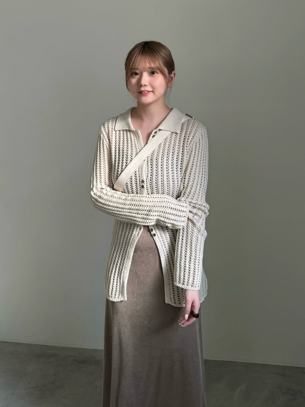 ベージュ系のスカート、ホワイト系のカーディガン/ボレロ、ホワイト系のショルダーバッグを着用したレディースの春コーディネートの2枚目の写真