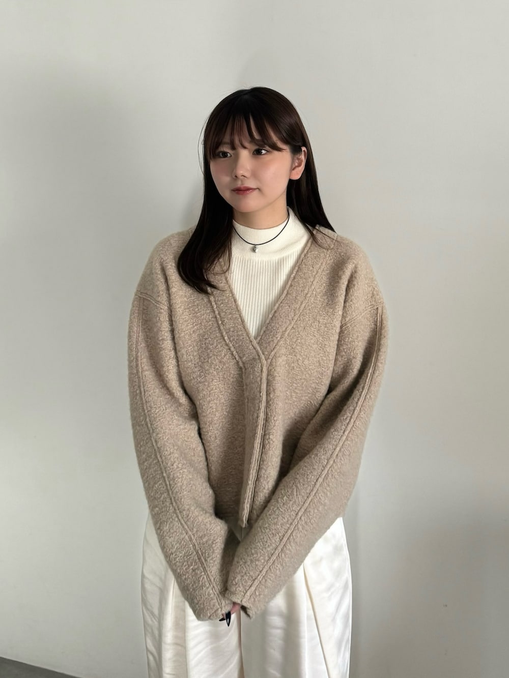 ベージュ系のカーディガン/ボレロ、ホワイト系のニット/セーター、ホワイト系のスラックスを着用したレディースの冬コーディネートの5枚目の写真