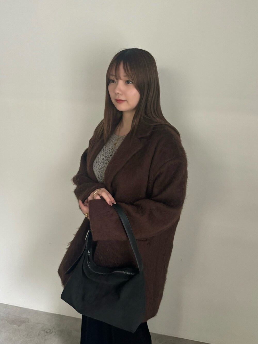 ブラウン系のテーラードジャケット、グレー系のニット/セーター、ブラック系のスカートを着用したレディースの秋コーディネートの4枚目の写真