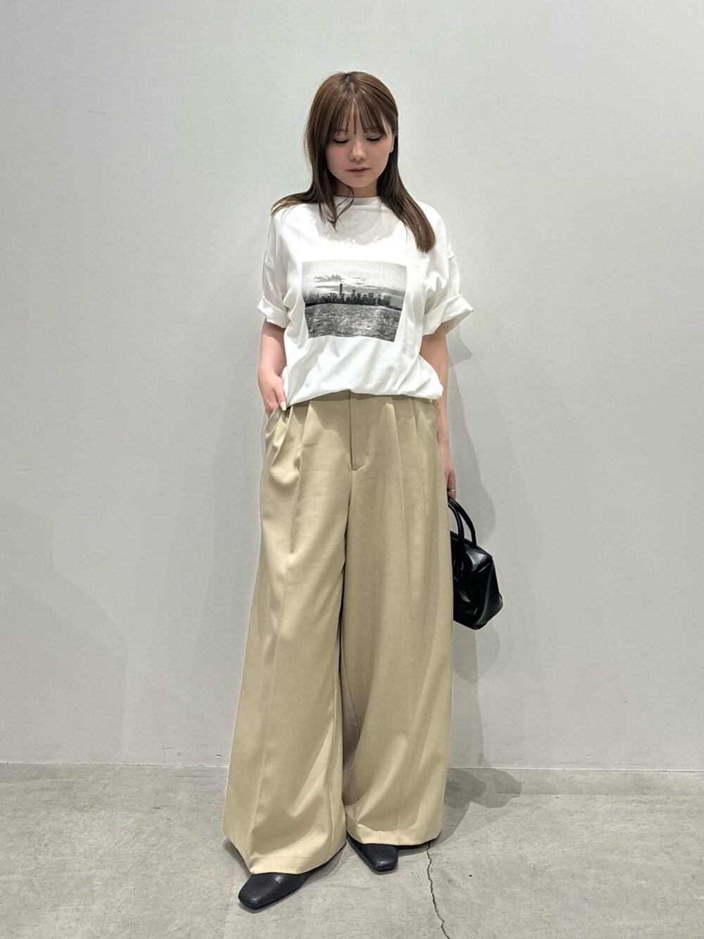 ホワイト系のTシャツ/カットソー、ベージュ系のスラックス、ブラック系のボストンバッグを着用したレディースの夏コーディネートの2枚目の写真