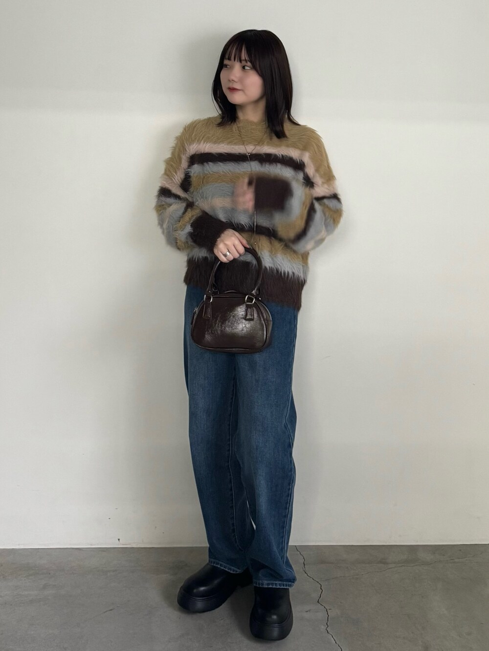 ブルー系のデニムパンツ、イエロー系のニット/セーター、ブラック系のブーツを着用したレディースの冬コーディネートの2枚目の写真
