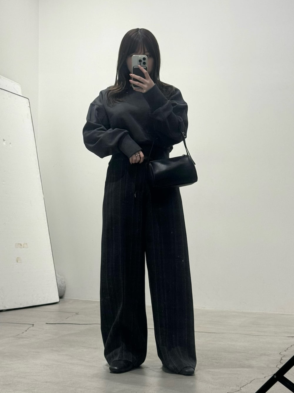 ブラック系のスウェット、ブラック系のスラックスを着用したレディースの冬コーディネートの5枚目の写真