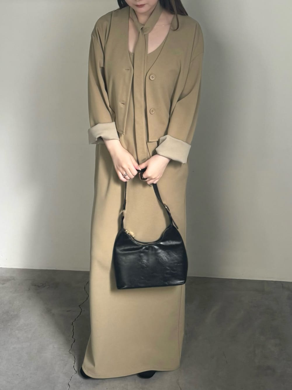 ベージュ系のセットアップ、ブラック系のハンドバッグ、ブラック系のスリッポンを着用したレディースの夏コーディネートの2枚目の写真