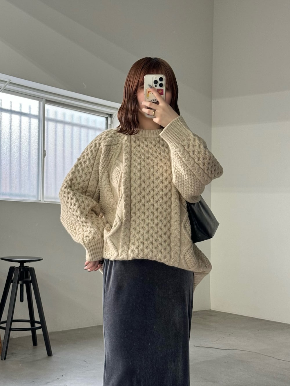 グレー系のスカート、ホワイト系のニット/セーター、ブラック系のハンドバッグを着用したレディースの秋コーディネートの5枚目の写真