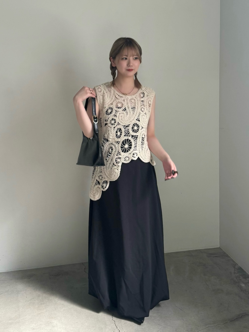 ブラック系のスカート、ブラック系のパンプス、ブラック系のハンドバッグを着用したレディースの春コーディネートの3枚目の写真