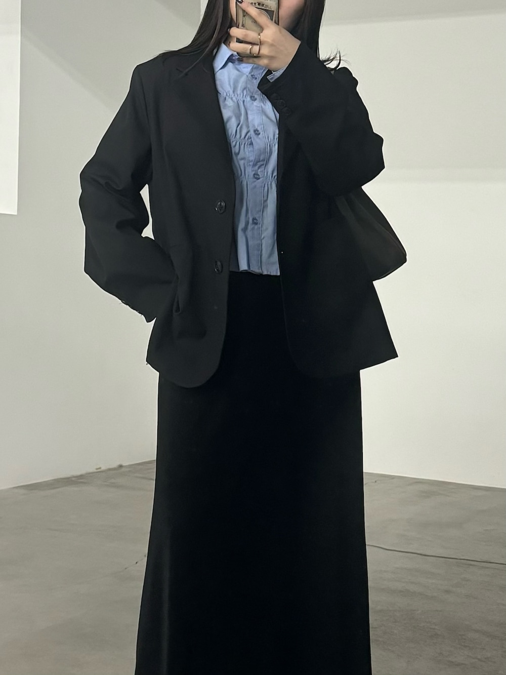 ブラック系のテーラードジャケット、ブルー系のシャツ/ブラウス、ブラック系のスカートを着用したレディースの秋コーディネートの2枚目の写真