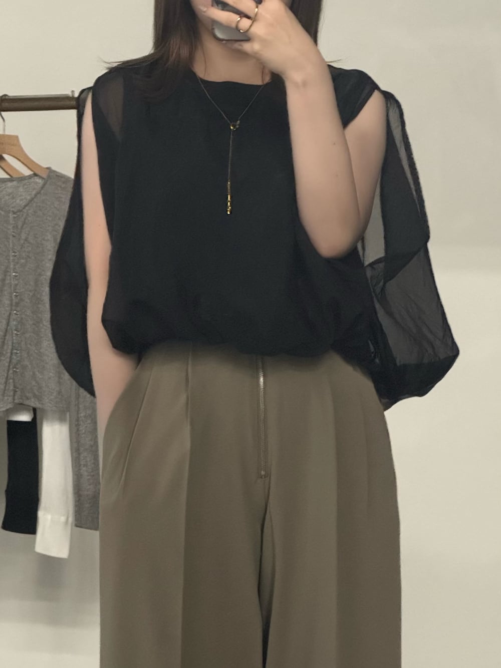 ブラック系のシャツ/ブラウス、ベージュ系のスラックス、ブラック系のスリッポンを着用したレディースの夏コーディネートの2枚目の写真