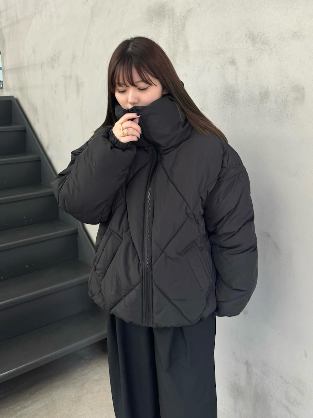 ピンク系のニット/セーター、ブラック系のダウンジャケット/コート、ブラック系のスラックスを着用したレディースの冬コーディネートの5枚目の写真