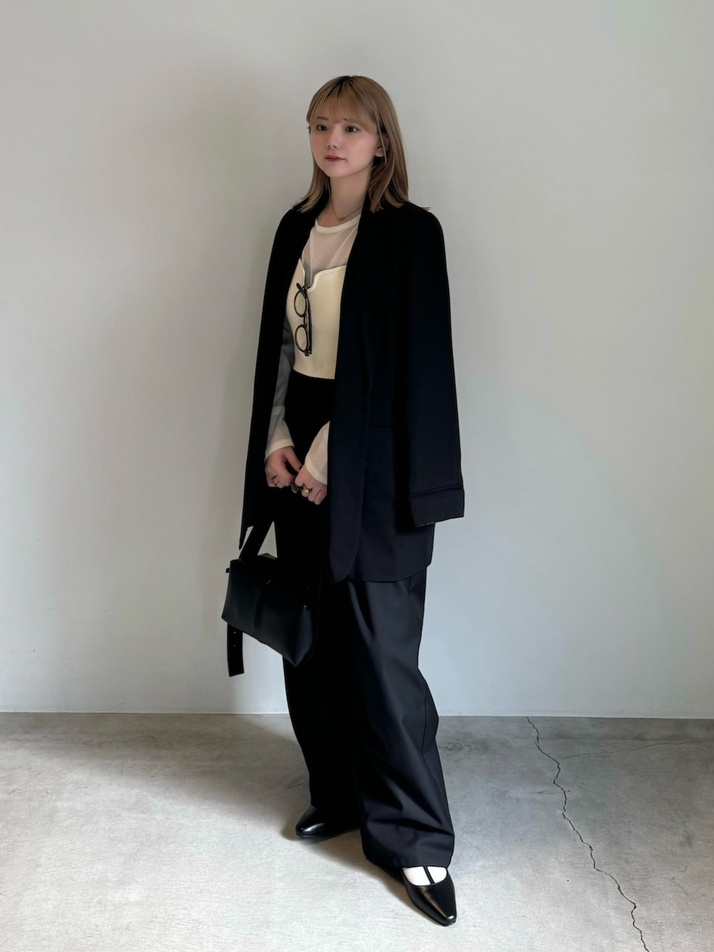 ブラック系のテーラードジャケット、ホワイト系のニット/セーター、ホワイト系のベストを着用したレディースの春コーディネートの4枚目の写真