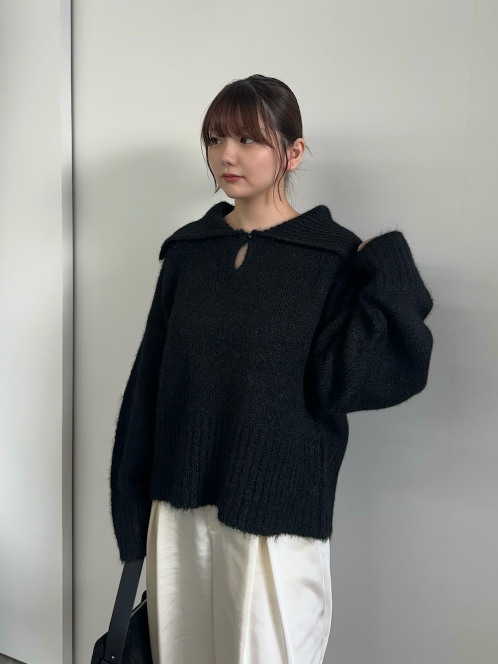 ブラック系のニット/セーター、ホワイト系のスラックス、ブラック系のハンドバッグを着用したレディースの冬コーディネートの3枚目の写真