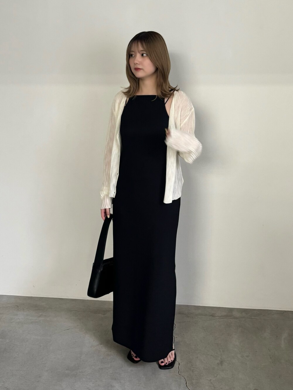 ブラック系のワンピース、ホワイト系のカーディガン/ボレロ、ブラック系のショルダーバッグを着用したレディースの夏コーディネートの3枚目の写真