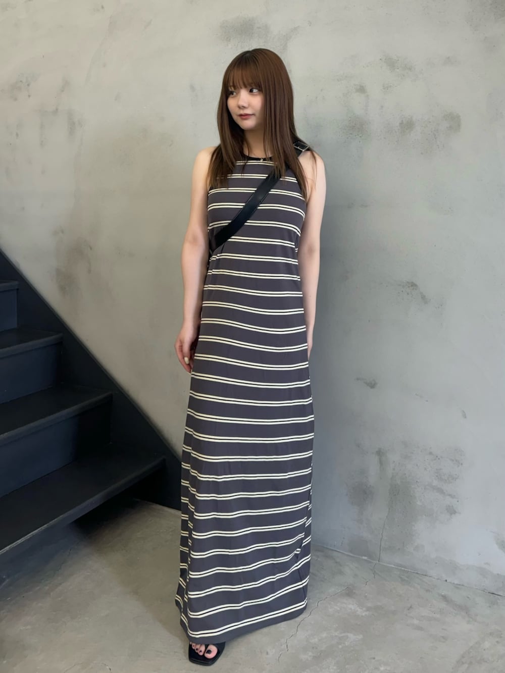 グレー系のワンピース、ブラック系のショルダーバッグ、ブラック系のサンダルを着用したレディースの夏コーディネートの3枚目の写真