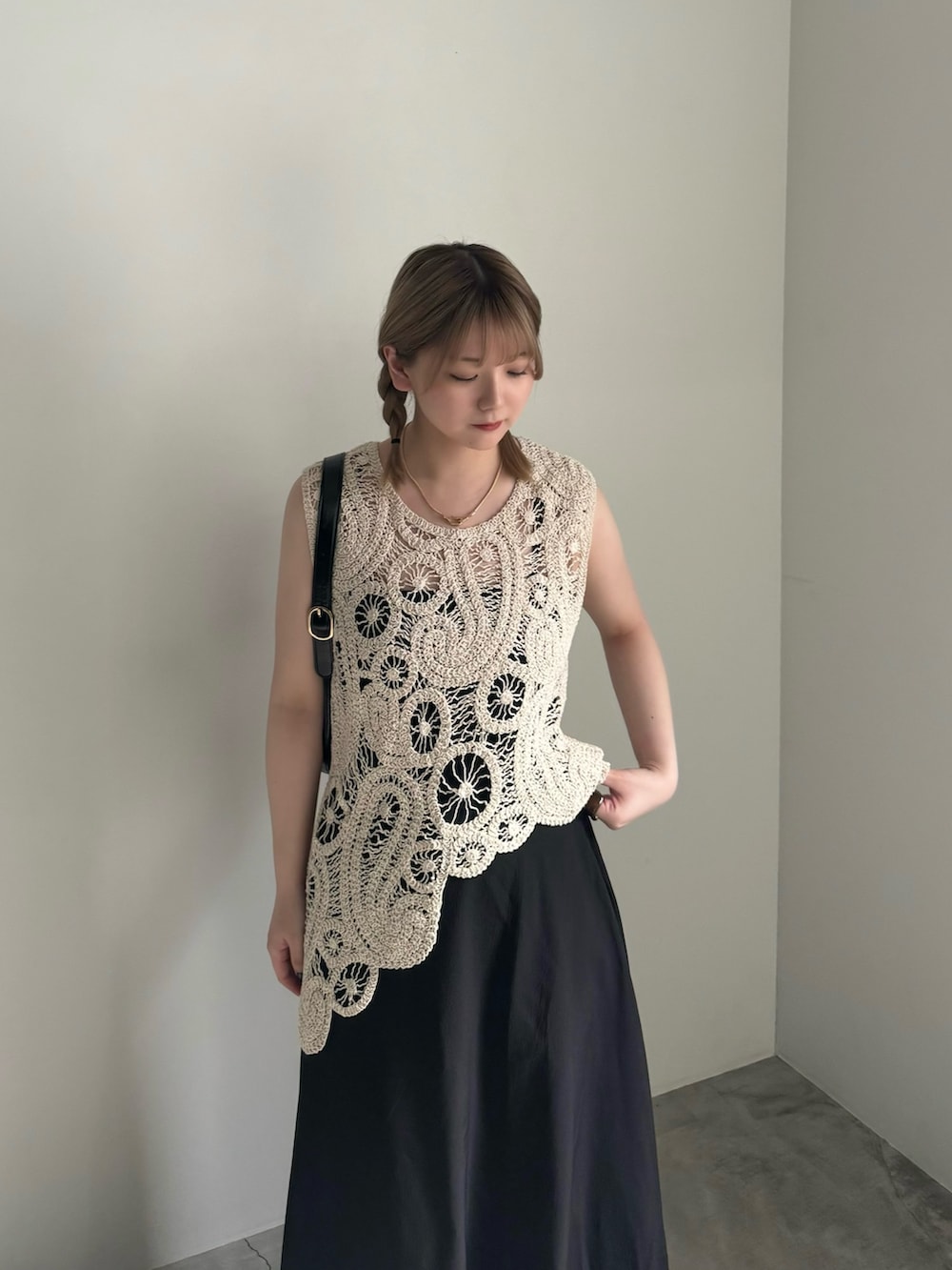 ブラック系のスカート、ブラック系のパンプス、ブラック系のハンドバッグを着用したレディースの春コーディネートの4枚目の写真