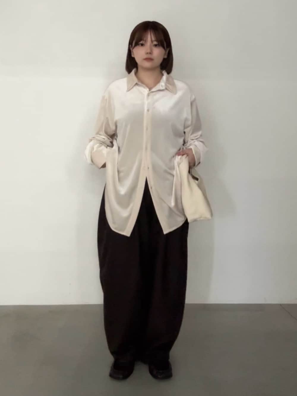 ベージュ系のシャツ/ブラウス、ブラウン系のスラックス、ベージュ系のハンドバッグを着用したレディースの秋コーディネートの2枚目の写真