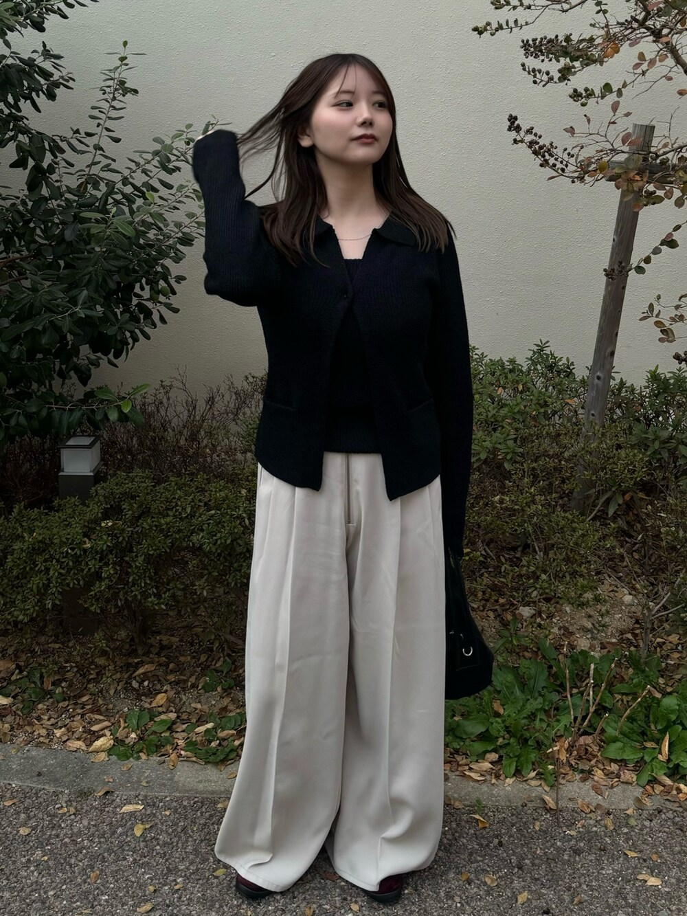 ブラック系のカーディガン/ボレロ、ホワイト系のスラックスを着用したレディースの秋コーディネートの2枚目の写真