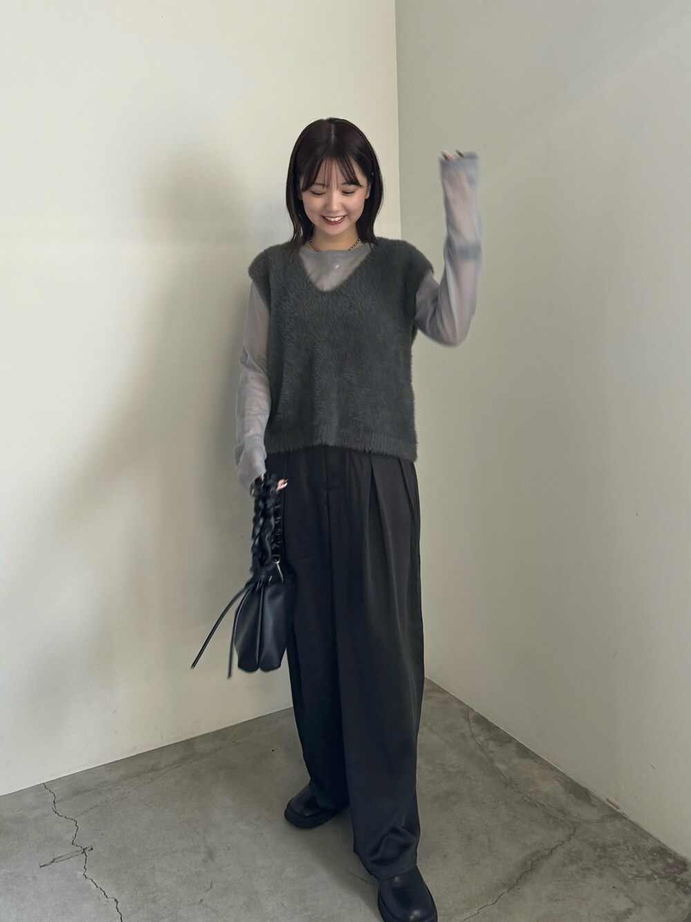 グレー系のベスト、グレー系のニット/セーター、ブラック系のスラックスを着用したレディースの秋コーディネートの2枚目の写真