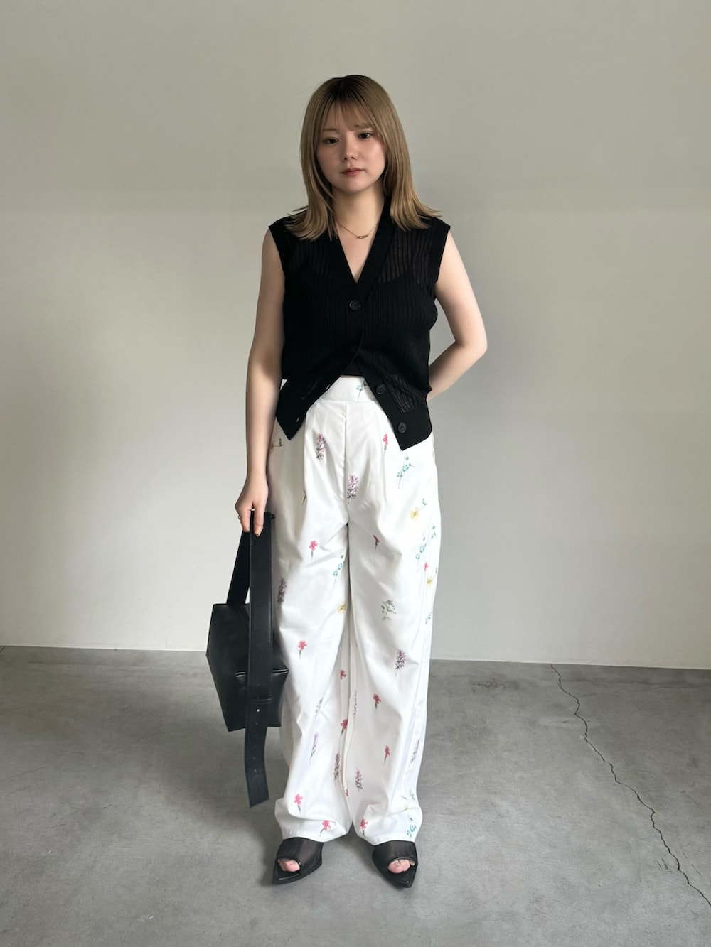 ブラック系のキャミソール、ブラック系のベスト、ブラック系のショルダーバッグを着用したレディースの春コーディネートの3枚目の写真