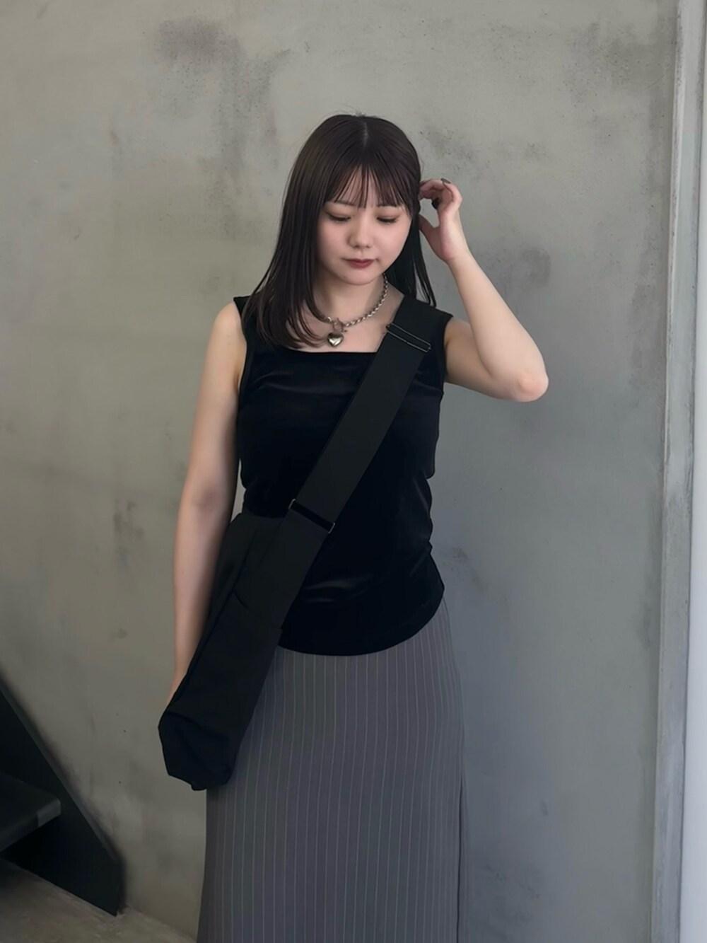 グレー系のスカート、ブラック系のショルダーバッグ、ブラック系のタンクトップを着用したレディースの夏コーディネートの5枚目の写真