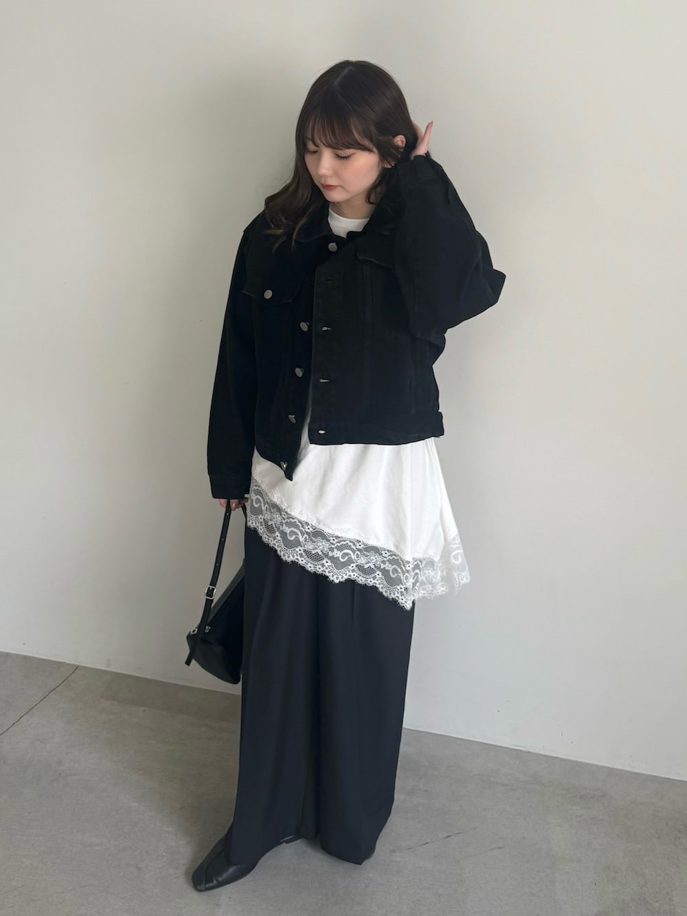 ブラック系のデニムジャケット、ブラック系のスラックスを着用したレディースの冬コーディネートの3枚目の写真