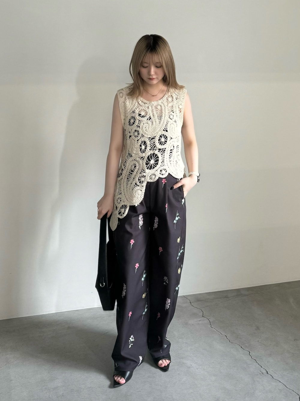 ホワイト系のベスト、ブラック系のキャミソール、ブラック系のショルダーバッグを着用したレディースの春コーディネートの3枚目の写真