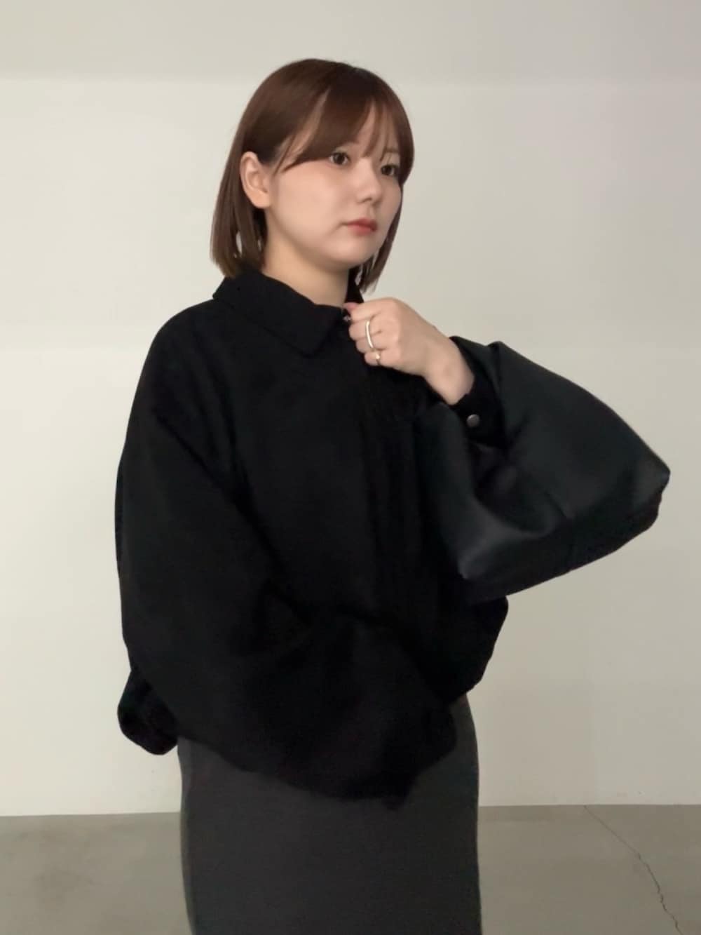 ブラック系のブルゾン、グレー系のスカート、ブラック系のハンドバッグを着用したレディースの秋コーディネートの3枚目の写真