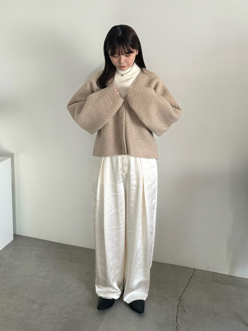 ベージュ系のカーディガン/ボレロ、ホワイト系のニット/セーター、ホワイト系のスラックスを着用したレディースの冬コーディネートの3枚目の写真