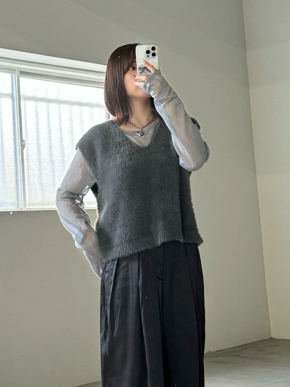 グレー系のベスト、グレー系のニット/セーター、ブラック系のスラックスを着用したレディースの秋コーディネートの5枚目の写真