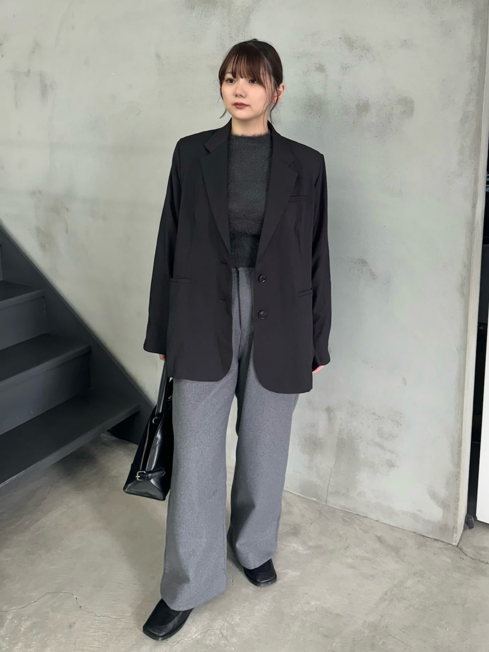 グレー系のニット/セーター、ブラック系のテーラードジャケット、グレー系のスラックスを着用したレディースの冬コーディネートの2枚目の写真